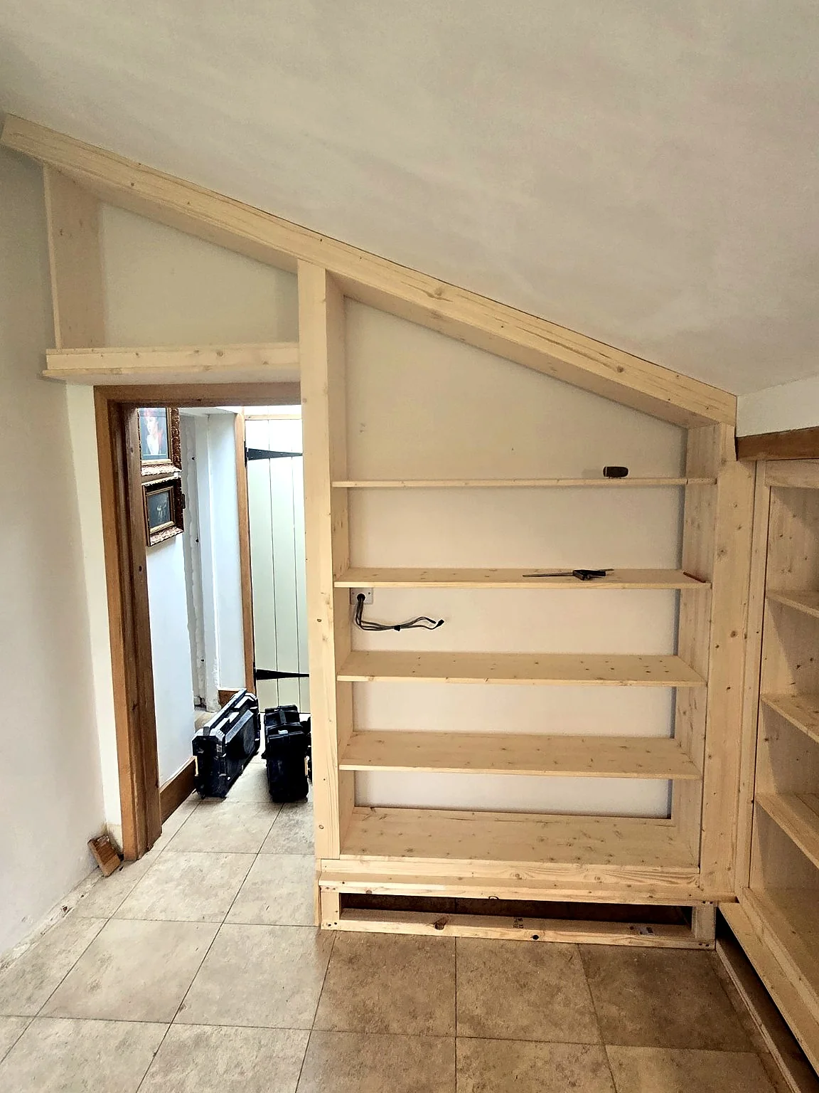 Angled bespoke built-in shelving made to fit a sloping ceiling by SM Installations