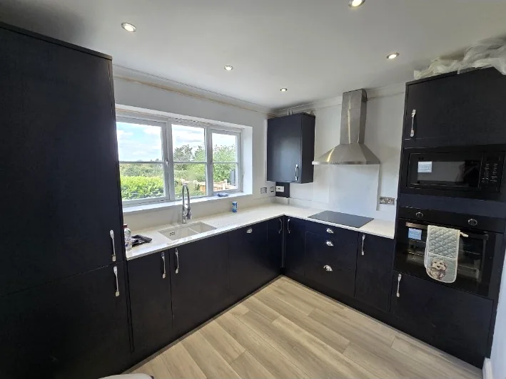 Dark fitted kitchen with integrated appliances completed by SM Installations